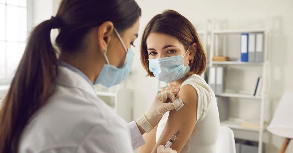 mujer con mascarilla siendo vacunada