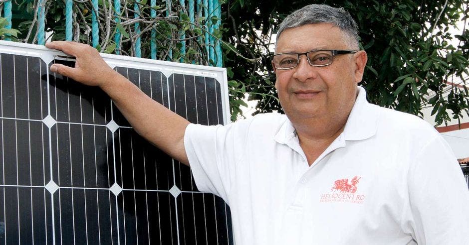 Hombre canoso de lentes con camisa blanca, junto a panel solar