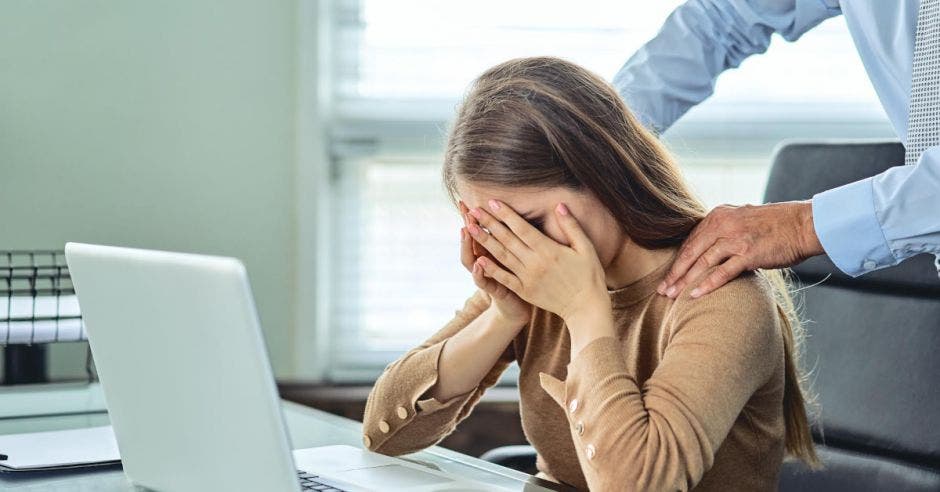 Un hombre toca la espalda de una mujer, mientras ella se lamenta