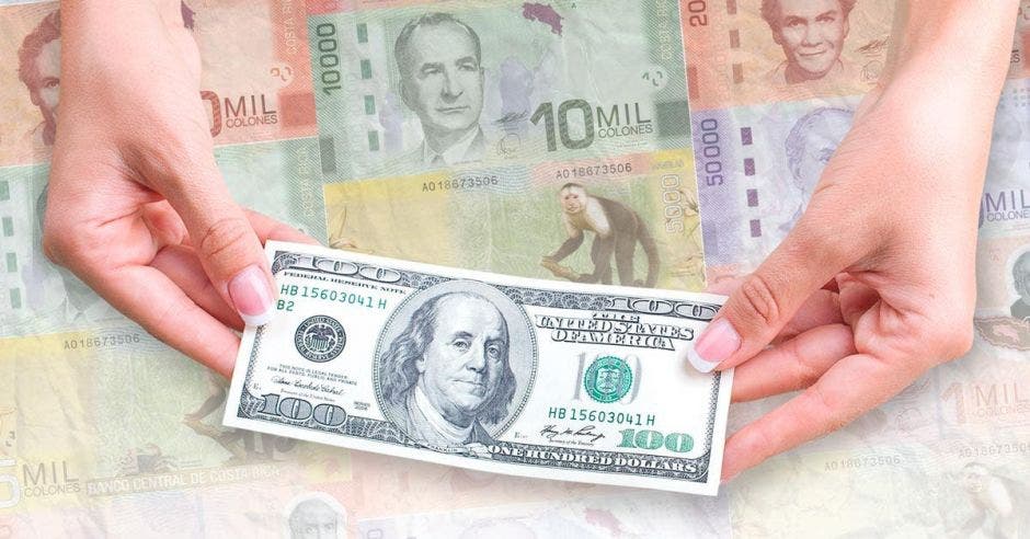 Billete de dólares con colones de fondo