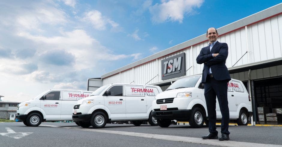 camionetas de entrega y señor con traje obscuro cruzado de brazos
