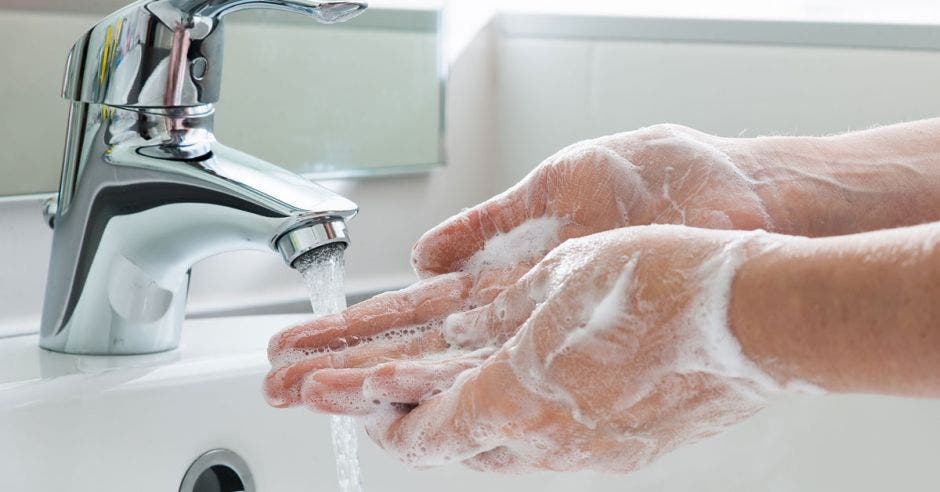 persona lavándose las manos con agua y jabón