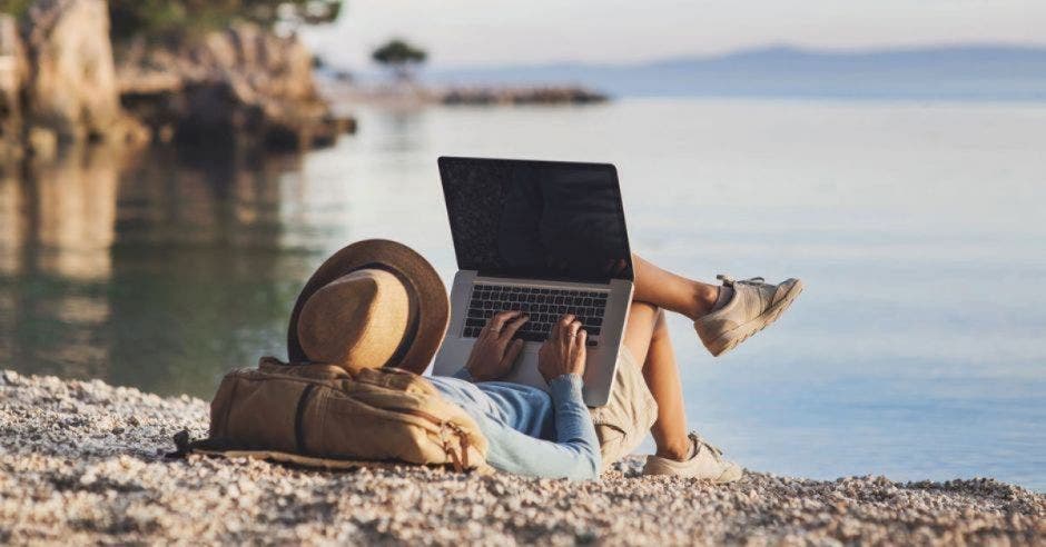 hombre sosteniendo computadora en la playa.