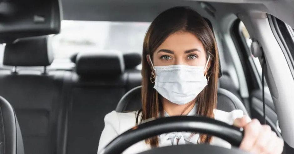 mujer con mascarilla conduciendo automóvil