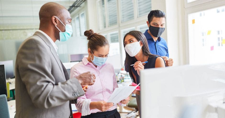 Un grupo de trabajadores en la oficina con mascarilla