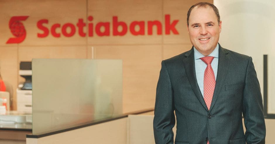 Hombre de traje frente a logo de Scotiabank