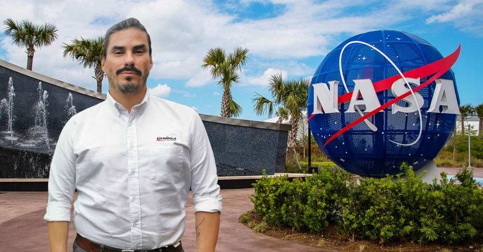 hombre de cabello cano con camisa blanca, de fondo instalaciones de la NASA