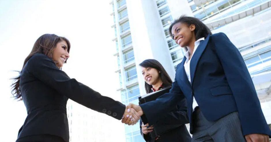 dos mujeres estrechando su mano en señal de trato