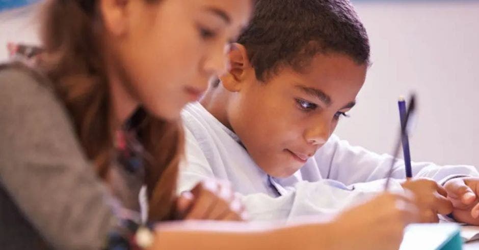 una niña y un niño escribiendo en sus cuadernos