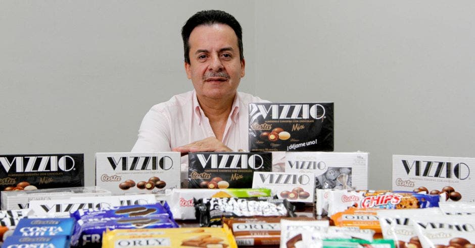 Walter Vega, Director Comercial de Ciamesa, detrás de una mesa llena de chocolates y galletas de las marcas Carozzi