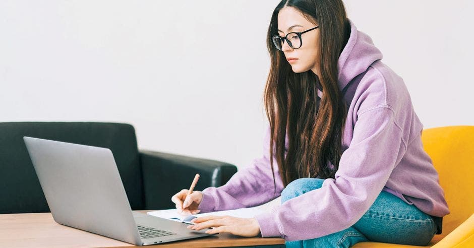 mujer joven en frente de la computadora estudiando