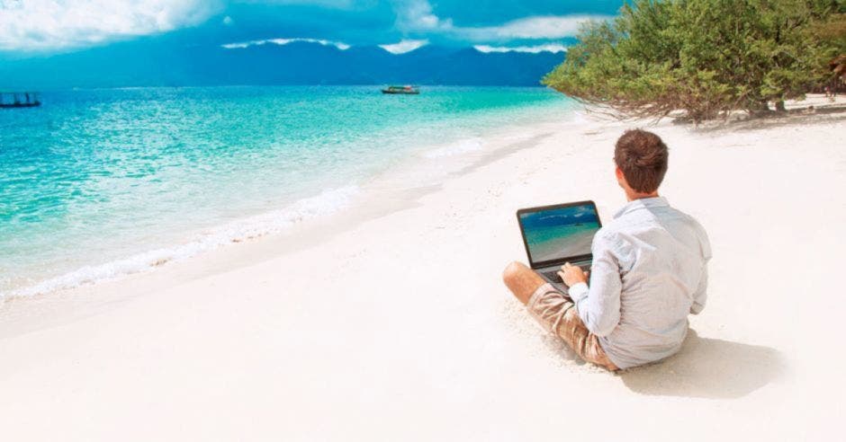 Turista con computadora en la playa