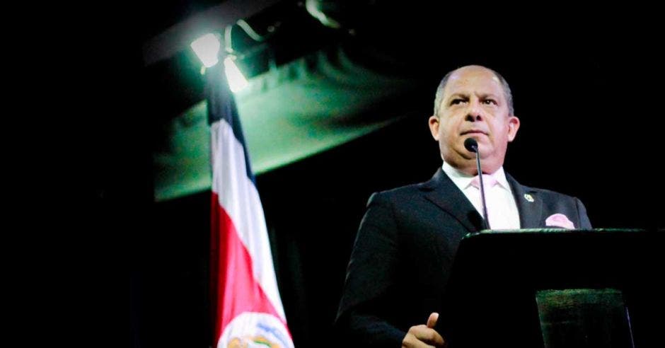 Luis Guillermo Solís en una conferencia con la bandera de Costa Rica atrás