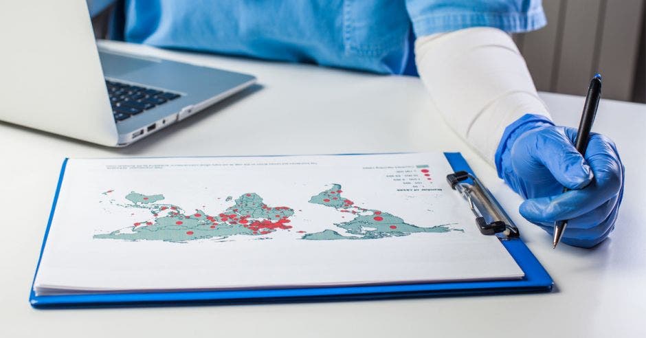 Una persona revisando un mapa que tiene muchos puntos rojos señalando los países más afectados por covid-19