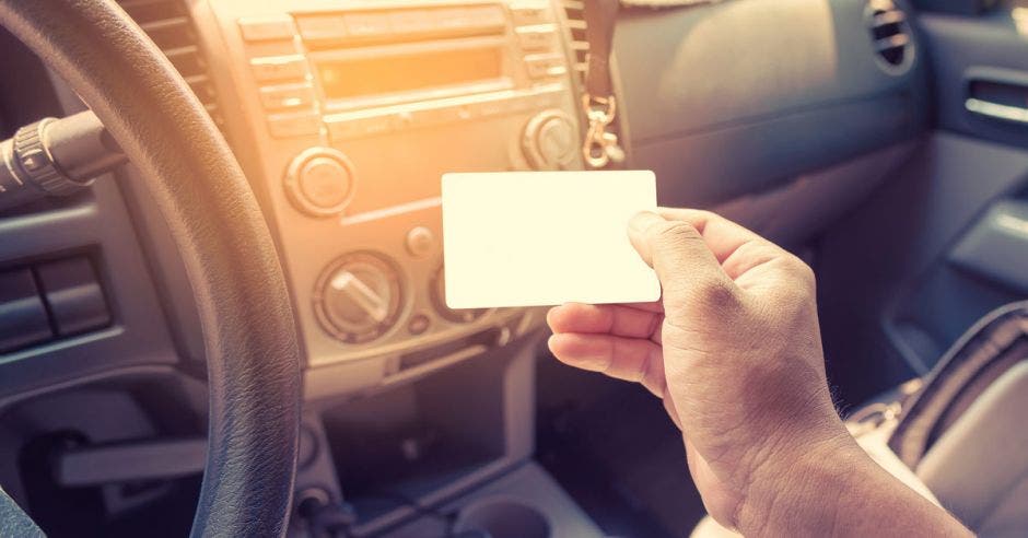 Persona en un auto mostrando la licencia de conducir