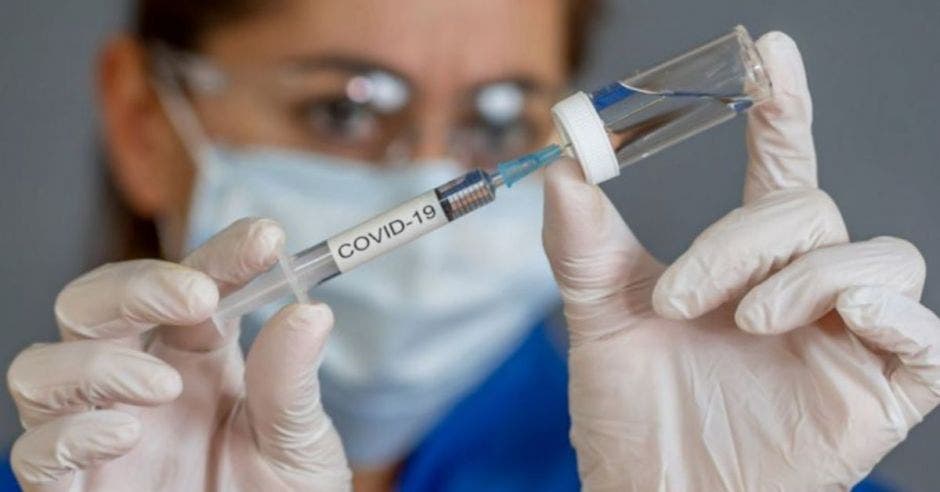 médico llenando una jeringa con vacuna Covid-19