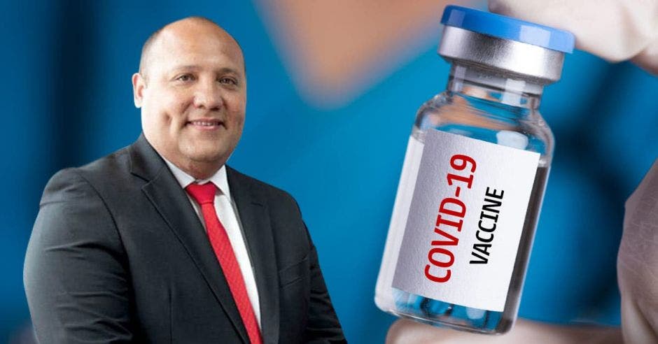 Mario Ruiz, gerente médico de la Caja con un arte de fondo de un frasco con dosis de vacuna contra la covid-19