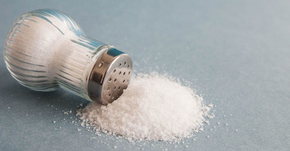 Un salero botado con sal esparcida en la mesa