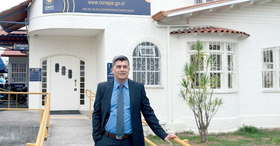 hombre con traje azul, fuera de edificio de Conape