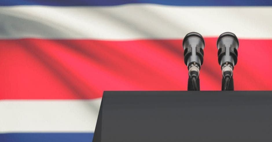 podio con micrófonos, de fondo bandera de Costa Rica
