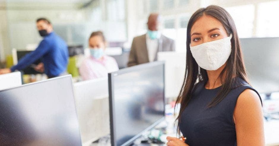 empleados con mascarilla trabajando en oficina