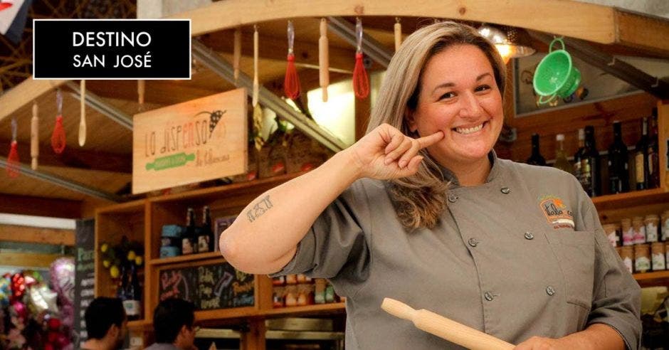 Cocinera joven sonriendo con restaurante de fondo