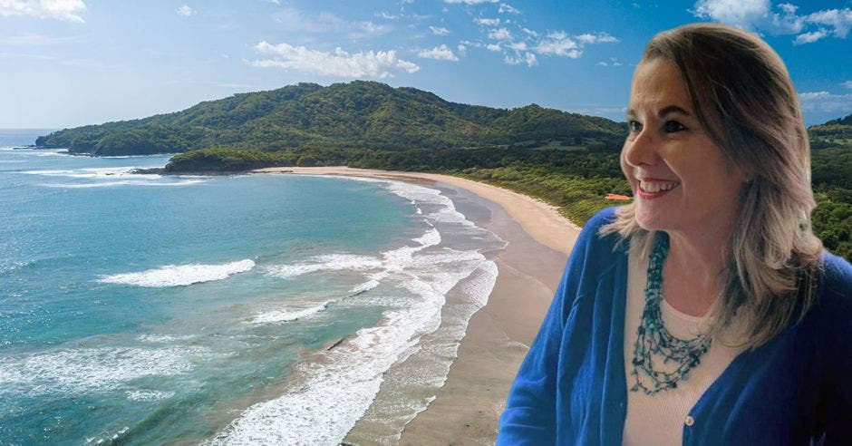 Una playa y al lado una mujer posando y sonriendo con blusa y collar azul.
